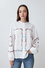 Camisa blanca con bordados florales en tonos rosa, azul y verde.