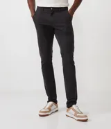 Pantalón masculino de sarga color beige, corte slim, con cierre de botón y cremallera, trabillas en la cintura y bolsillos delanteros y traseros.