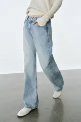 Jeans de tiro bajo, corte recto y largo completo, con efecto lavado y detalles de rotos en el delantero. Cierre frontal con cremallera y botón, y diseño de cinco bolsillos.