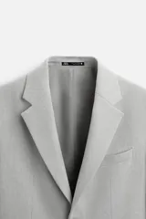 Blazer straight fit color gris claro confeccionado en tejido con viscosa. Tiene cuello con solapas de muesca, manga larga acabada en puño con botón, bolsillo de vivo en pecho, bolsillos de plastrón en cadera y bajo con aberturas en espalda. Cierre frontal de botonadura.