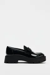 Zapato tipo mocasín negro acharolado con antifaz y suela track.