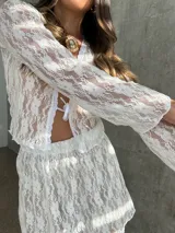 Top blanco de encaje elastizado con mangas largas y cierre frontal con lazo.