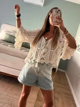 Blusa tejida calada color crudo, con diseño geométrico y motivos florales. Presenta escote redondeado y mangas 3/4 con leve vuelo.