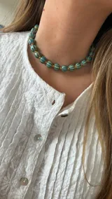 Collar corto de cuentas turquesas con rayas horizontales blancas y separadores dorados.