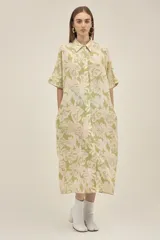 Vestido camisero largo de lino color verde claro con estampado de flores blancas, estilo oversize, con cuello camisero, mangas cortas, bolsillos laterales y botones de madera. Marca Polonio, hecho en Italia.