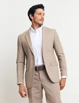 Traje de vestir color tostado, compuesto por saco con solapa de muesca, cierre de dos botones, bolsillos con solapa y pantalón de corte recto.