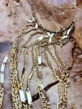 Collar dorado con flecos de cadenas finas y dijes rectangulares.
