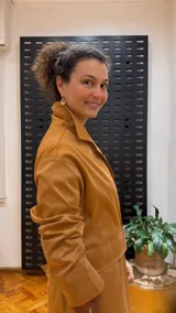 Gabardina color mostaza con cuello camisero, cierre frontal con botones y cinturón con hebilla.