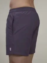 Short de baño verde con estampado de margaritas blancas y cordón ajustable naranja.