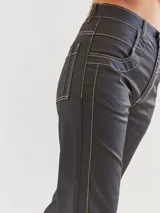 Pantalón jean recto color negro con costuras blancas contrastantes.