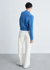Sweater color crema de punto trenzado con cuello alto.