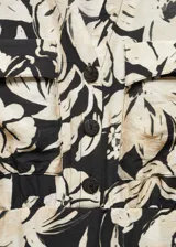 Vestido corto camisero con estampado floral en blanco y negro, cuello camisero, manga 3/4 con puños abotonados, cierre frontal con botones y falda con abertura lateral.