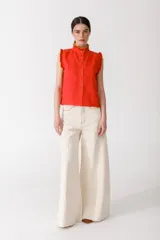 Blusa color mostaza sin mangas con cuello alto y volados en color borgoña en cuello, sisas y ruedo. Cierre frontal con botones.