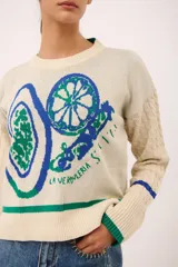 Sweater azul marino de punto con cuello redondo y mangas largas con diseño trenzado. Presenta un estampado de frutas y verduras con la inscripción "La verdulería S.A.".