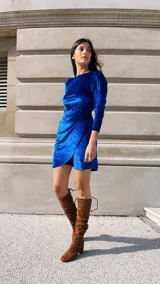 Vestido corto fucsia de terciopelo, con mangas largas abullonadas y falda drapeada.