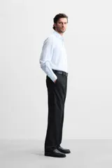 Camisa celeste a rayas verticales, de corte regular, confeccionada en algodón, con cuello italiano, manga larga con puños abotonados y cierre frontal con botones.