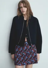 Chaqueta bomber color negro con forro interior, cierre delantero con cremallera y cuello redondo.