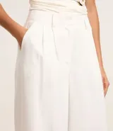 Pantalón de vestir blanco, de corte palazzo, con trabillas en la cintura, bolsillos laterales y pliegues delanteros.