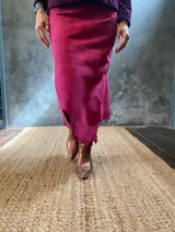 Pollera midi de gamuza color fucsia, con cierre lateral y ruedo irregular. Fabricada en Uruguay.