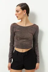 Top corto de fiesta color negro con brillos, de mangas largas y cuello redondo.