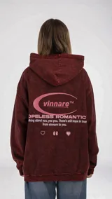 Buzo hoodie color borgoña con efecto lavado, confeccionado en algodón. Estampado en la espalda con el logo de la marca "vinnare™" y la frase "HOPELESS ROMANTIC".