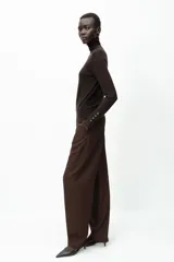 Jersey negro de punto liso con cuello alto, manga larga y detalle de botones dorados en los puños.