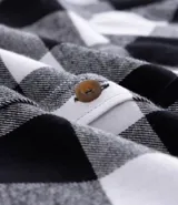 Camisa de franela a cuadros rojos y negros, de corte regular, manga larga y cuello inglés.