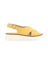 Sandalia amarilla de cuero con tiras cruzadas, suela de plataforma blanca y hebilla metálica de ajuste.