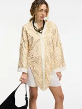 Camisa color crema con bordado dorado, botones frontales y lazos en el frente.