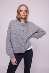 Cárdigan tejido a crochet color gris, con cuello redondo, mangas abullonadas, botones grandes y terminaciones acanaladas.