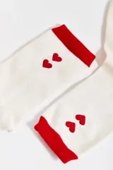Par de medias blancas con puño rojo, dos corazones rojos bordados y logo "CaroCuore" en rojo.