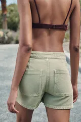 Falda pantalón corta color crudo, de tiro alto con delantero cruzado y cierre con cremallera oculta y botones.
