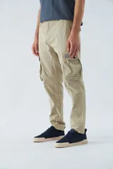 Pantalón cargo color marrón, corte slim, con cierre y botón en la cintura, pasacintos y bolsillos cargo con botones.