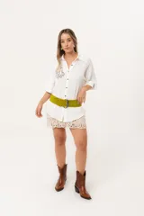 Camisa blanca de silueta oversize, con cuello camisero, manga 3/4 y corte más largo en la espalda. Presenta bordados de coral y caracol en el frente, y botones a tono.