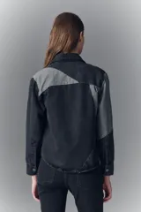 Campera recta de denim rígido negro con recortes en gris. Tiene bolsillos con solapa y botones metálicos.