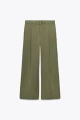 Pantalón verde militar de tiro medio con bolsillos delanteros y falsos bolsillos traseros. Detalle de pinzas en el delantero. Cierre frontal con cremallera y botón. Corte ancho.