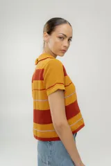 Remera tejida a rayas horizontales color marrón, celeste y blanco, con cuello polo y mangas cortas.