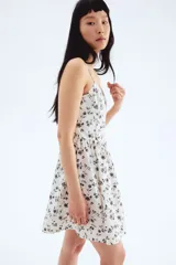 Vestido corto blanco con estampado floral negro, breteles finos, escote corazón y falda con vuelo.