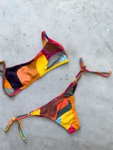 Conjunto de bikini con estampado a cuadros azul y blanco, compuesto por un corpiño bandeau con breteles regulables y una bombacha vedetina con tiras laterales para atar.
