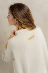 Sweater tejido en hilo de algodón color crudo, con cuello redondo, corte holgado, hombros caídos y diseño de ochos en la parte delantera.