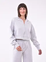 Campera blanca con capucha y cierre frontal, de corte cropped y mangas largas.