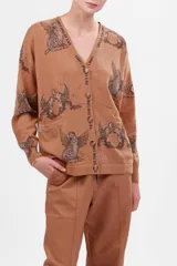 Cárdigan color marrón claro con estampado de aves, lunas y estrellas. Tiene escote en V, cierre con botones y bolsillos delanteros.