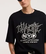 Remera negra de algodón con textura y corte oversized. Presenta estampa frontal con lettering gótico, siglas 'NY' dentro de un círculo y coordenadas geográficas.