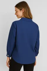 Blusa blanca de poliéster, corte holgado, con cuello camisero y cierre parcial con botones.