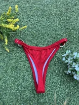 Bikini de dos piezas color rojo, con corpiño triángulo que tiene una argolla central de zamak y bombacha colaless con argollas laterales. La tela es texturada.