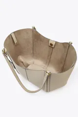 Bolso de hombro tipo shopper color beige, con doble asa y cierre imantado. Incluye una cartera interior con cierre de cremallera.