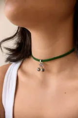 Gargantilla con cordón rojo y dije de cerezas rojas con detalles dorados y hojas verdes.