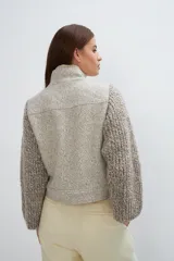 Campera con cuello alto y mangas de tejido de punto, con cierre frontal de botones ocultos y bolsillos de doble abertura.