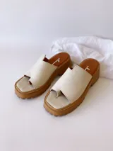 Sandalias de cuero crudo con tira ancha sobre los dedos y suela track color caramelo.