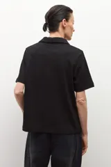 Camisa de manga corta color ciruela, con cuello camisero y cierre frontal de botones.